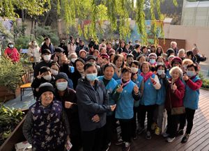 A group of fifty plus volunteers pose for a picture in the garden.