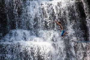 boy jumps into a waterfall