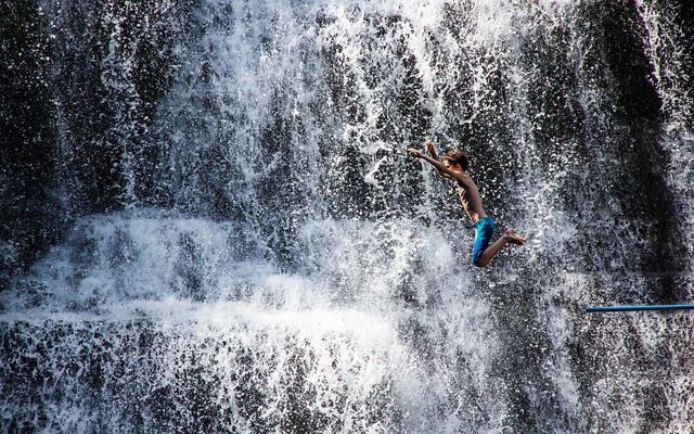 boy jumps into a waterfall