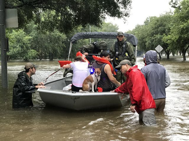 A man, woman and a dog sit in a rescue boat as emergency responders stand in waist-deep floodwaters in the outskirts of Houston during Hurricane Harvey.