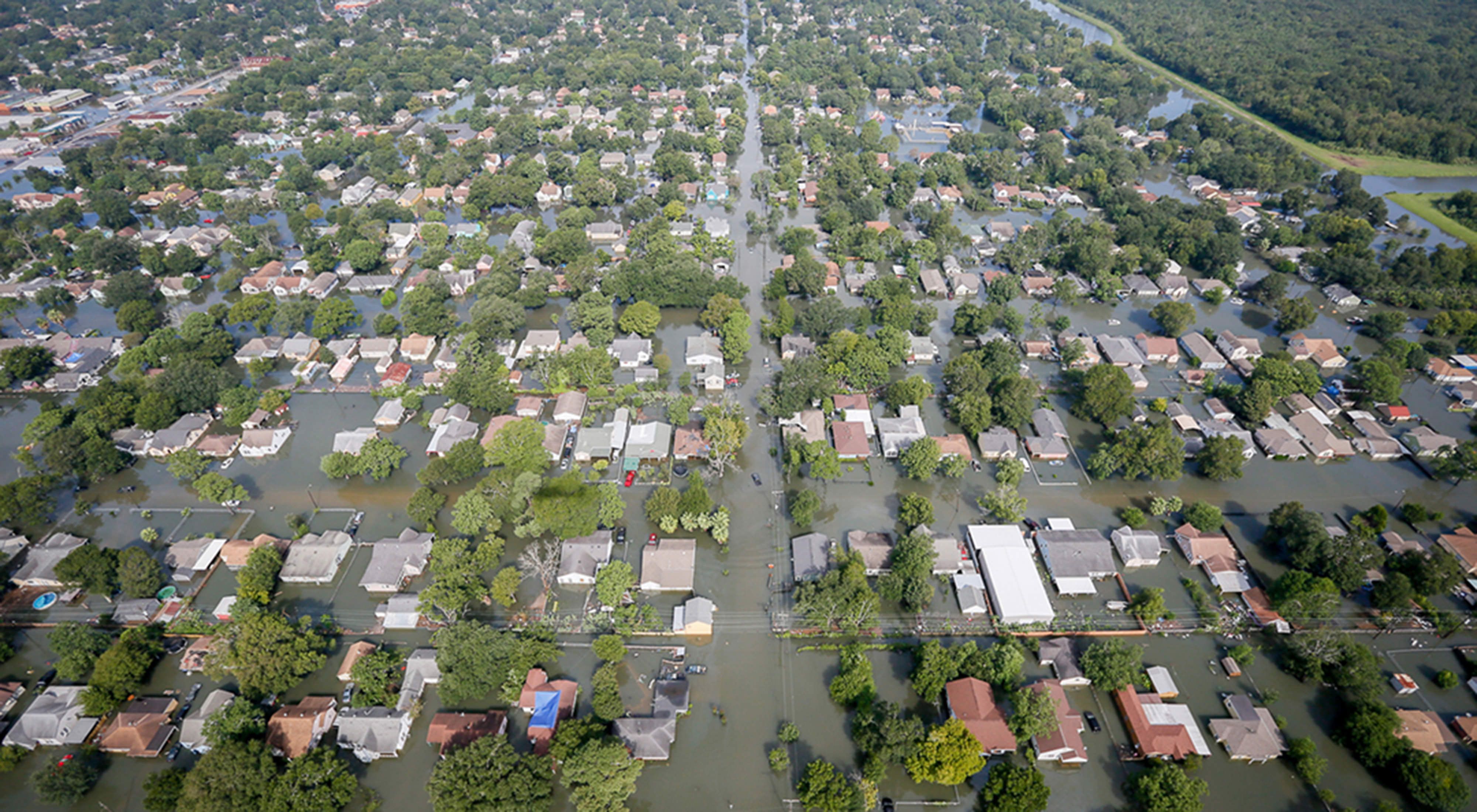 An aerial view of a Houston neighborhood with flood water rising to rooftops.