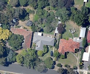 An aerial view of 3 houses surrounded by tree canopy
