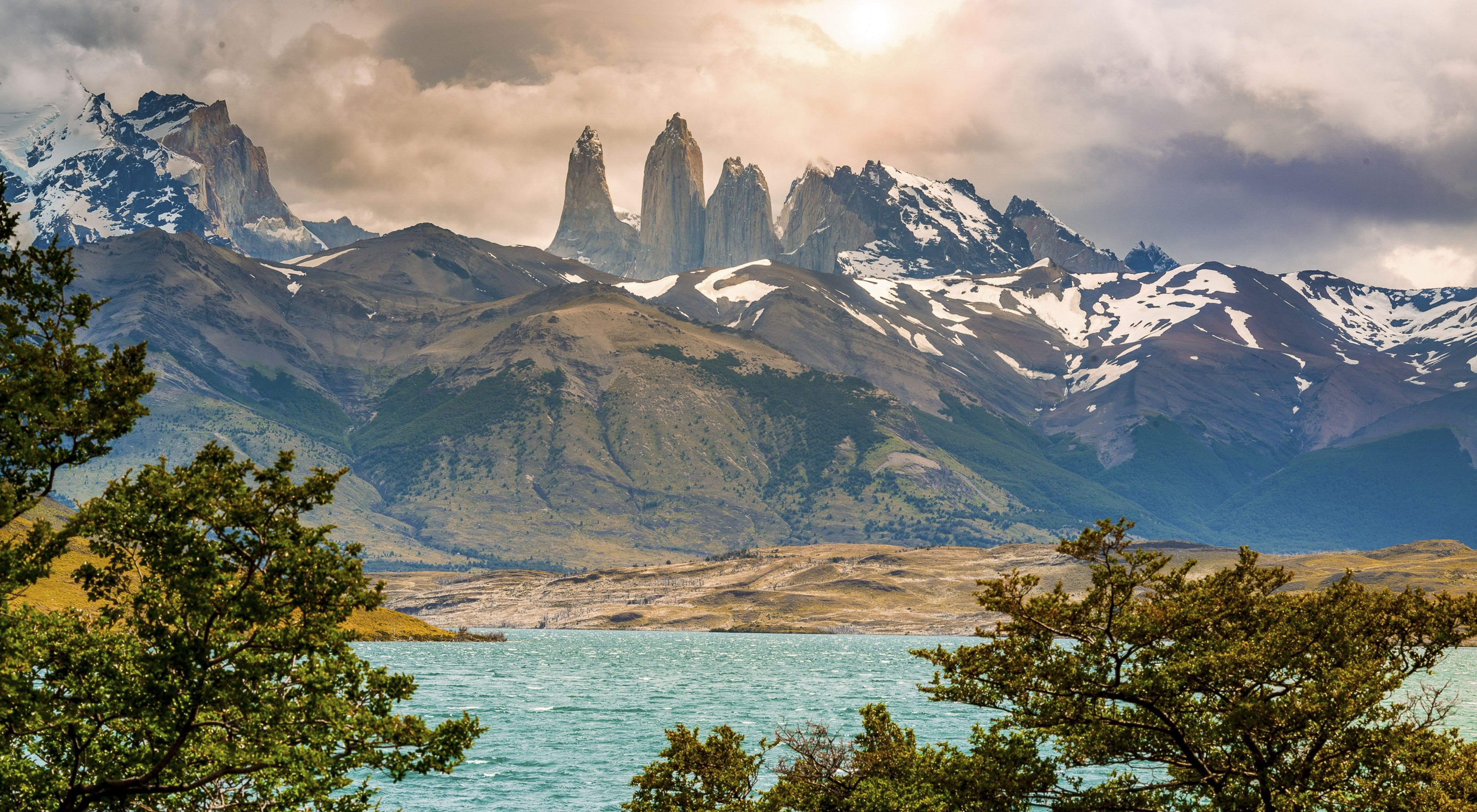 Parque Nacional Torres del Paine in Chile, showing sparkling waters of a bay and steep, snow-covered mountains in the distance.