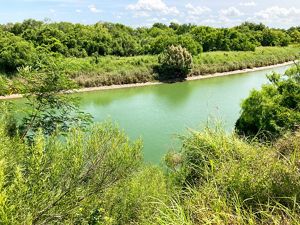 A turquoise blue river is lined with dense vegetation on both sides of its banks.