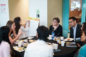 A group of people sit and converse at a round table.