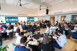 A group of people sit at round tables in a meeting room.