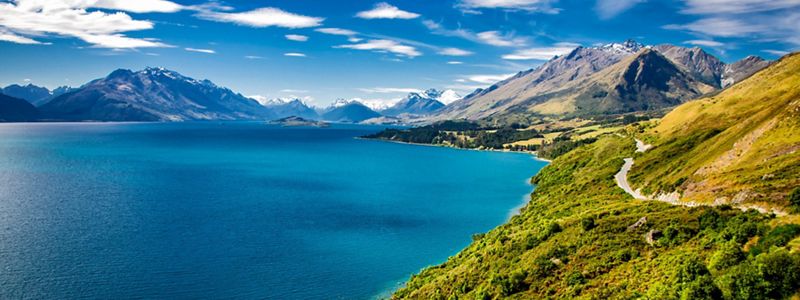 Landscape view of vibrant blue waters of a large lake surrounded by mountains.