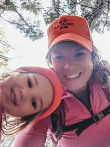 Molly Payne Wynne y su joven hija en pie entre varios árboles se toman un retrato cercano a sus rostros.