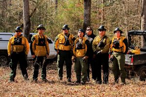 Seven members of the Alabama-Coushatta Tribe of Texas stand ready in their protective gear before a prescribed burn.