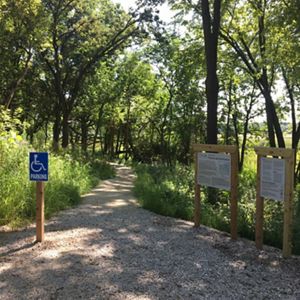 an accessible trailhead lines with trees and grasses.