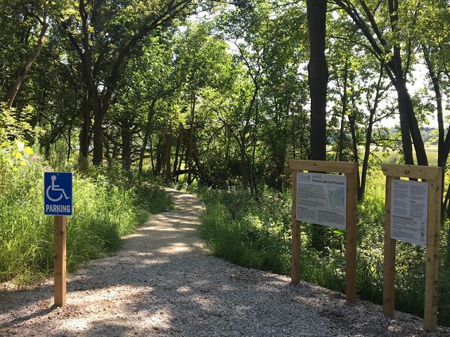 an accessible trailhead lines with trees and grasses.