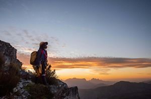 Women in climbing gear standing on edge of cliff.