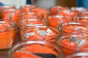 Closeup of several glass jars filled with pieces of fresh salmon.