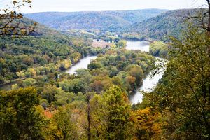 A vista view down into a valley with a river that winds through forested lands.