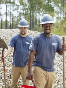 Two young men in hard hats holding shovels.