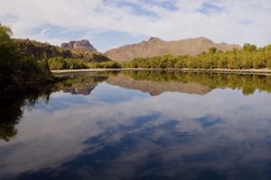 View looking across a large flat body of water toward mountains in the distance.