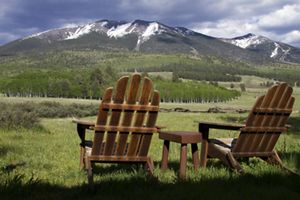 Two wooden chairs facing snowy mountains