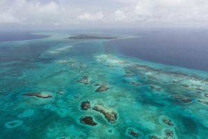 Aerial view of the turquoise waters of Belize’s Lighthouse Reef, with Long Caye in the distance.