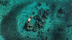 A boy snorkelling through shallow waters on a reef.