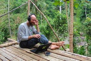 A man listening to headphones sitting in a tree house.
