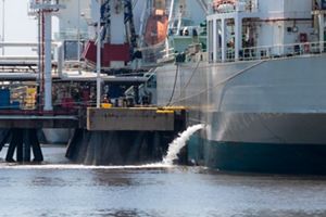 A docked ship emptying its ballast water via a hole in the side. 