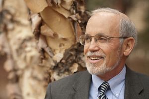 A man wearing glasses smiles poses for a picture.