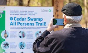 A man takes a photo of a sign with his phone.