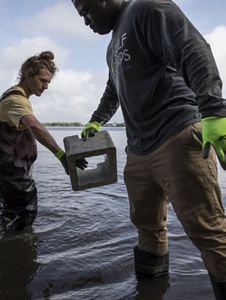 One crew member passes a concrete block to another.