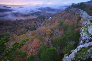 Orange and green trees in the fall sit next to a bluff in Arkansas.
