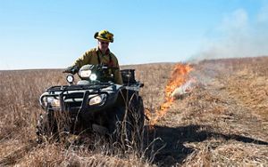 A burn boss rides an ATV and lights a controlled burn on the preserve.