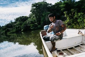 A man holds a fishing line in a boat on a river