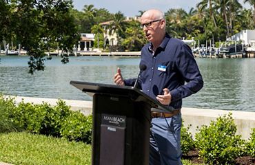 A man stands behind a podium and speaks at the Brittany Bay Living Shoreline.