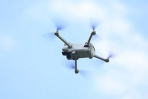 Drone voando com céu azul ao fundo.