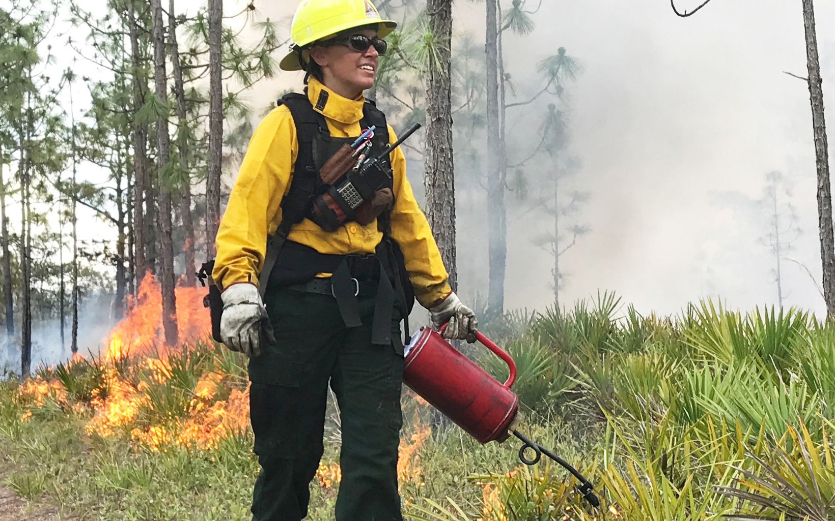 Igniting Inspiration Land conservation coordinator Cody-Marie Miller sets the woods alight with a drip torch during a prescribed burn at The Disney Wilderness Preserve.  © Zach Prusak/TNC