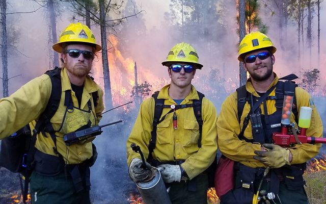 Three students from the University of Idaho learn prescribed fire techniques from staff at Tiger Creek Preserve. 
