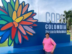 Mujer tomandose una foto de frente con el logo COP16 en el fondo.