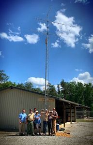 People stand in a circle around a tall radio pole.