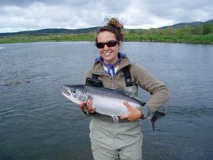 TNC scientist in Alaska's Bristol Bay holding a fish as she stands in a lake.