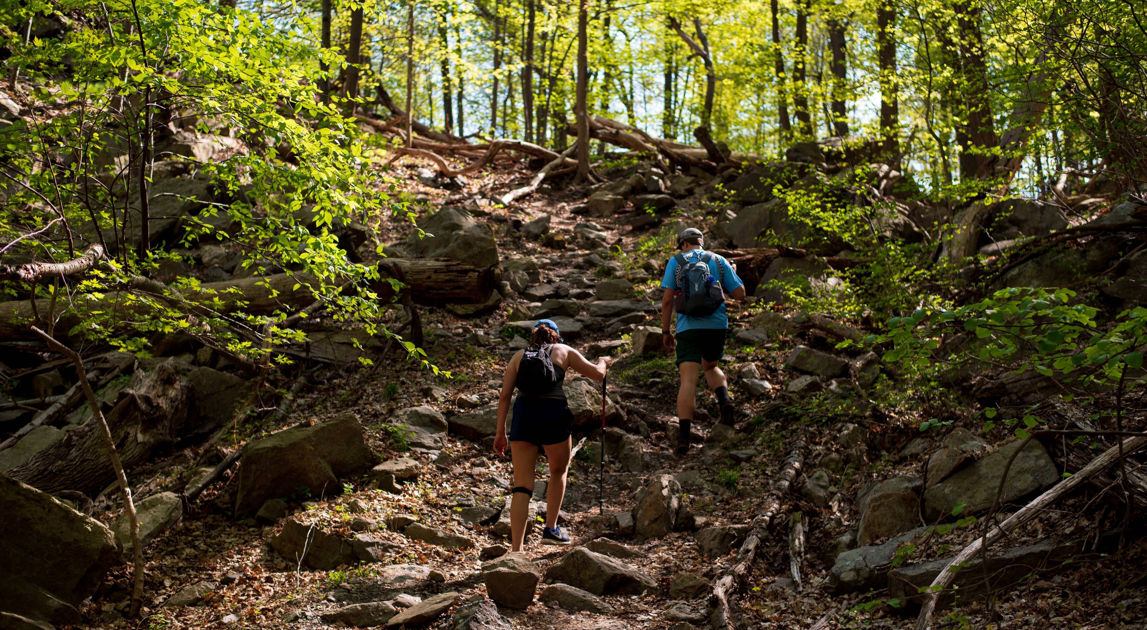 Two hikers walking upwards along a sloping trail.