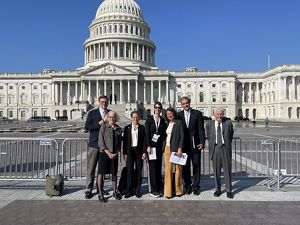 A group of people in suits standing in front of the U.S. Capitol building.