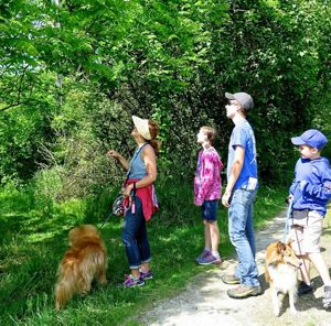 Family and 2 dogs on a trail looks into forest.