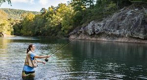 A women standing in water fishing.