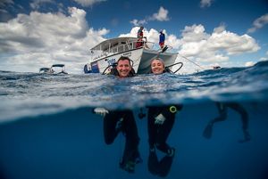 a man and woman in diving gear float in the water