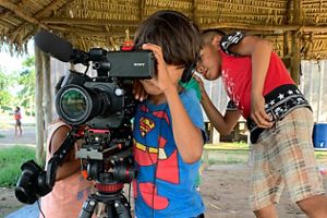 Crianças indígenas bricando com câmera de vídeo.
