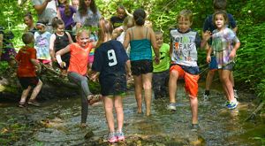 A group of children having a blast stomping around in a creek.
