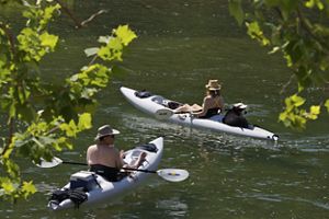 Two kayakers in a river on a sunny day. 