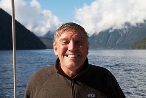 headshot of a smiling white man outside near water