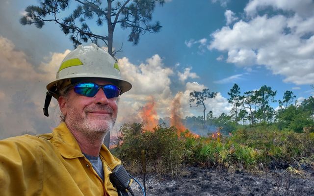 Florida fire program director David Printiss stands against a controlled burn in a forest at Apalachicola Bluffs and Ravines Preserve. 