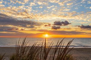The sun rises over the ocean in Rehoboth Beach creating an orange reflection in the water. 