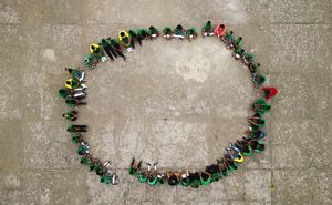 Aerial view looking down at a large group of teachers and students sitting in a large circle on the ground.